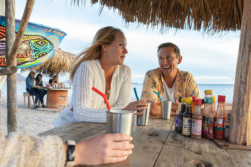 Couple at beach shack with steel pints